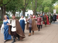 Personas ataviadas con trajes medievales, durante el desfile que les llevara hasta la parroquia a celebrar misa medieval