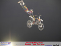 Motocicleta en el aire y el piloto tumbado literalmente por encima de la moto, en una de las acrobacias realizadas durante el espectáculo de Summer Night tour 2014 en Manzanares